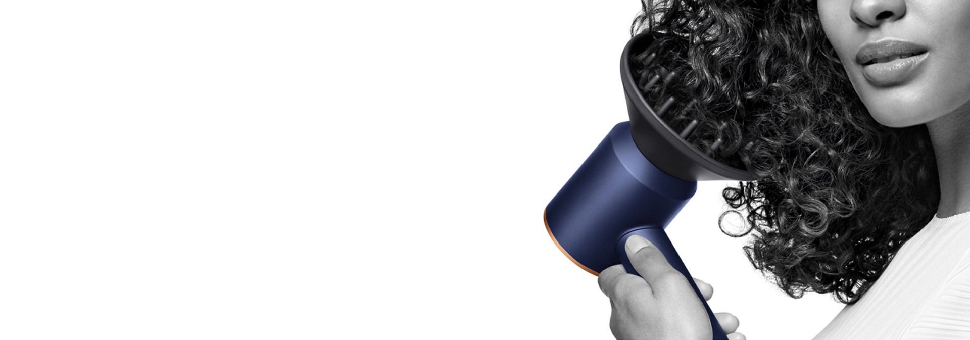The Dyson Supersonic hair dryer used by a model on their hair to diffuse their curls.