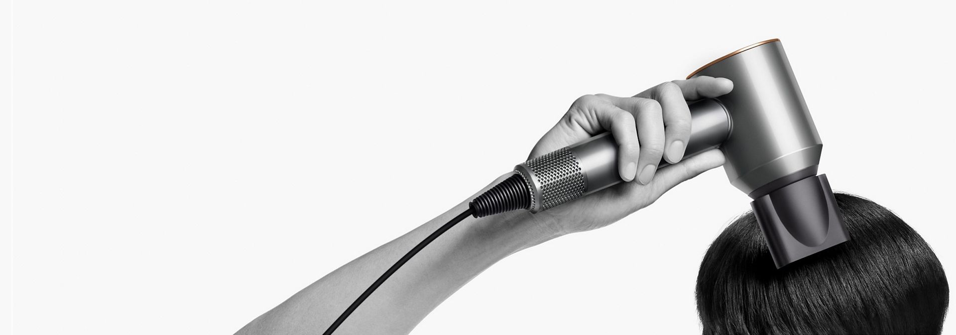The Dyson Supersonic Origin hair dryer used by a model to style their hair.