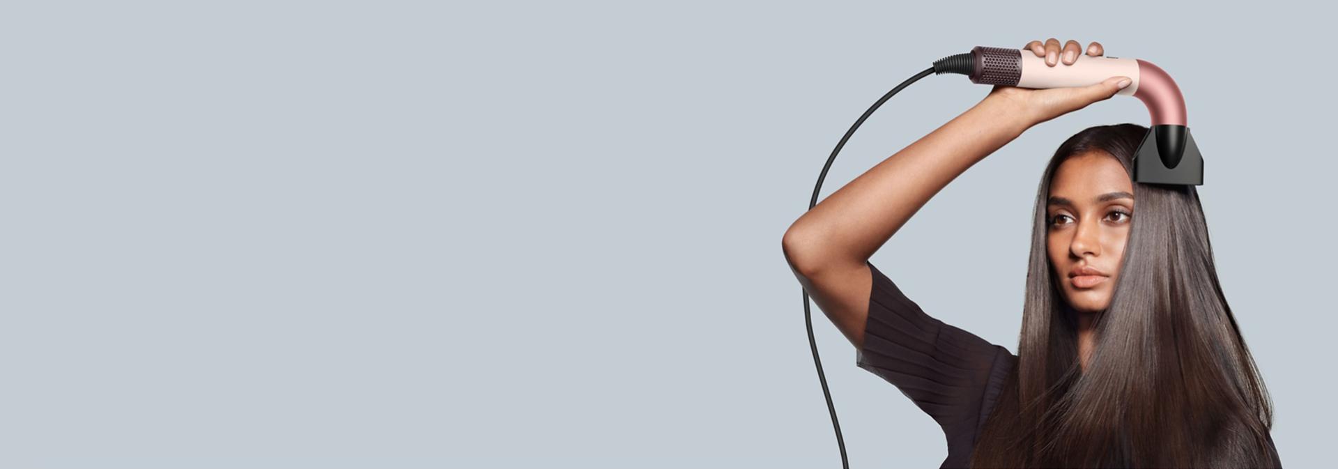 Bir model, saçını kurutmak için Dyson Supersonic saç kurutma makinesini kullanıyor.