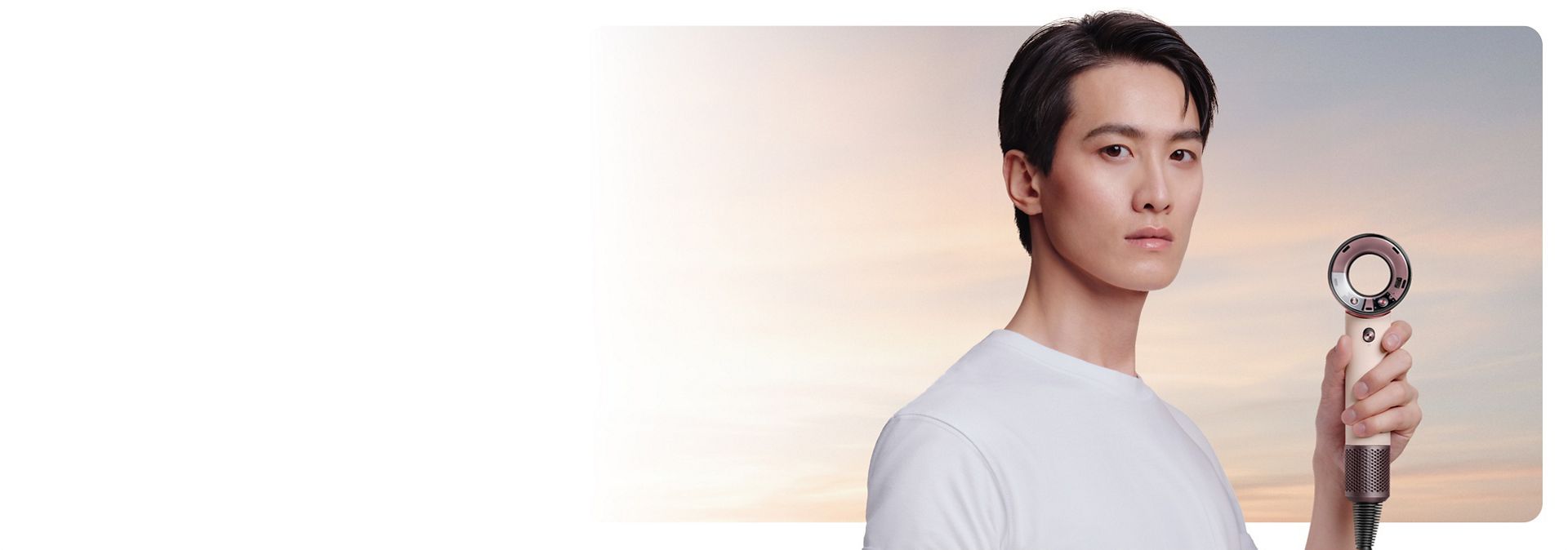 Model holds the Dyson Supersonic Travel hair dryer to one side.