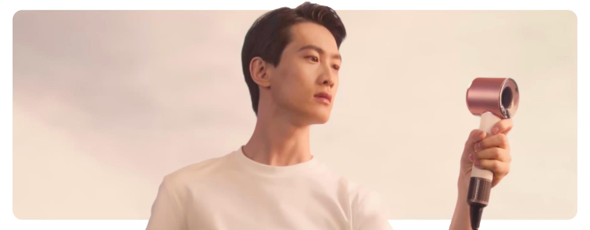 Model holds the Dyson Supersonic Travel hair dryer in front of them.