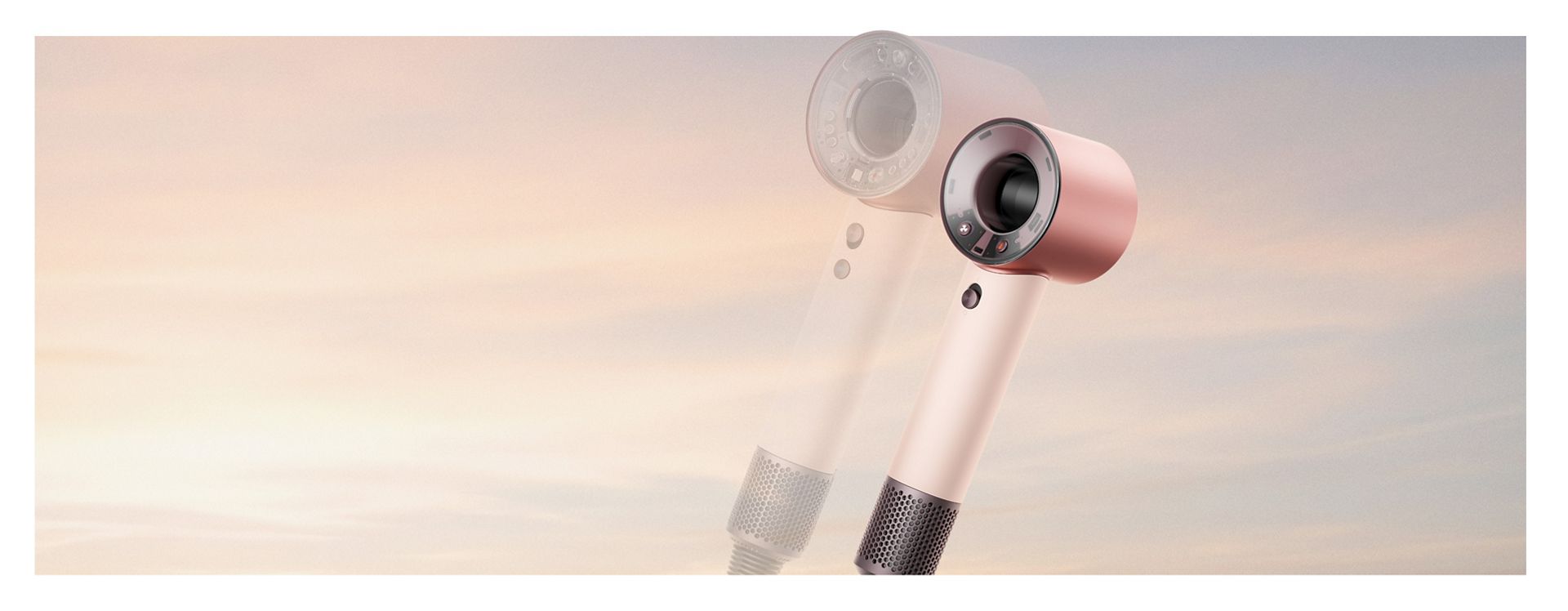 Dyson Supersonic Travel hair dryer in front of a sunrise and a transparent Dyson Supersonic Nural hair dryer.