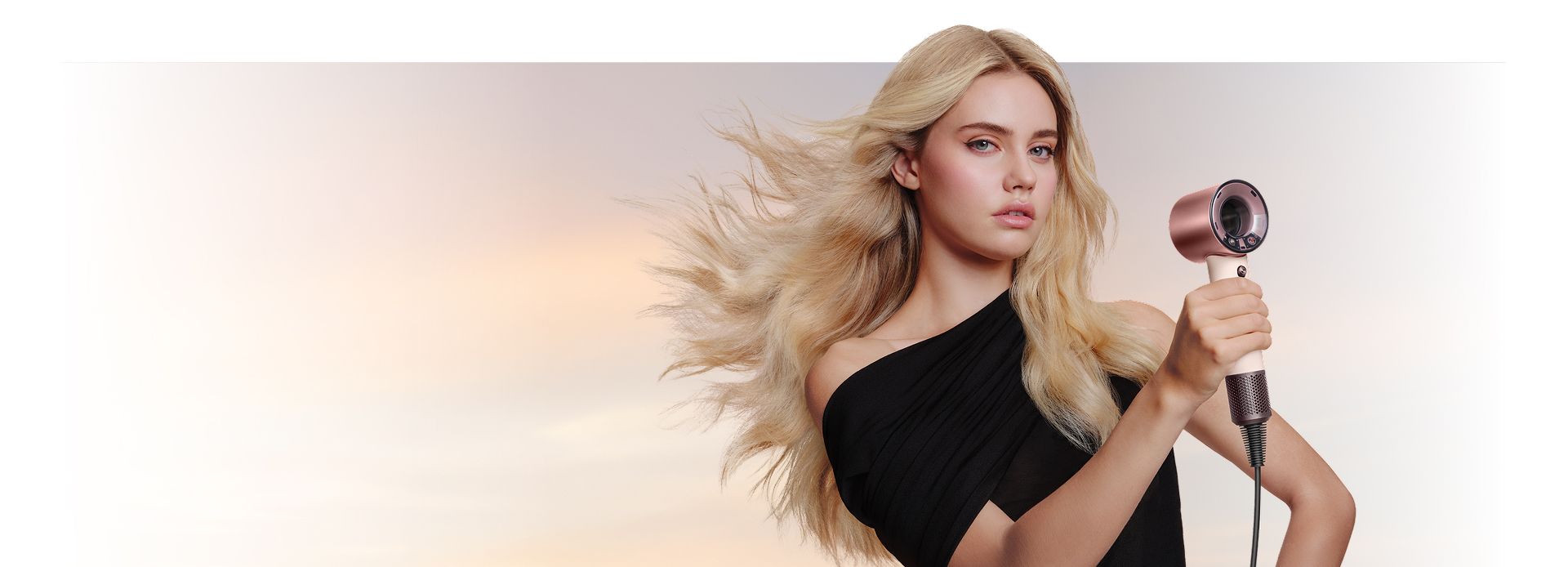 A female model with straight and wavy styling dries her blonde hair with the Dyson Supersonic Travel hair dryer.