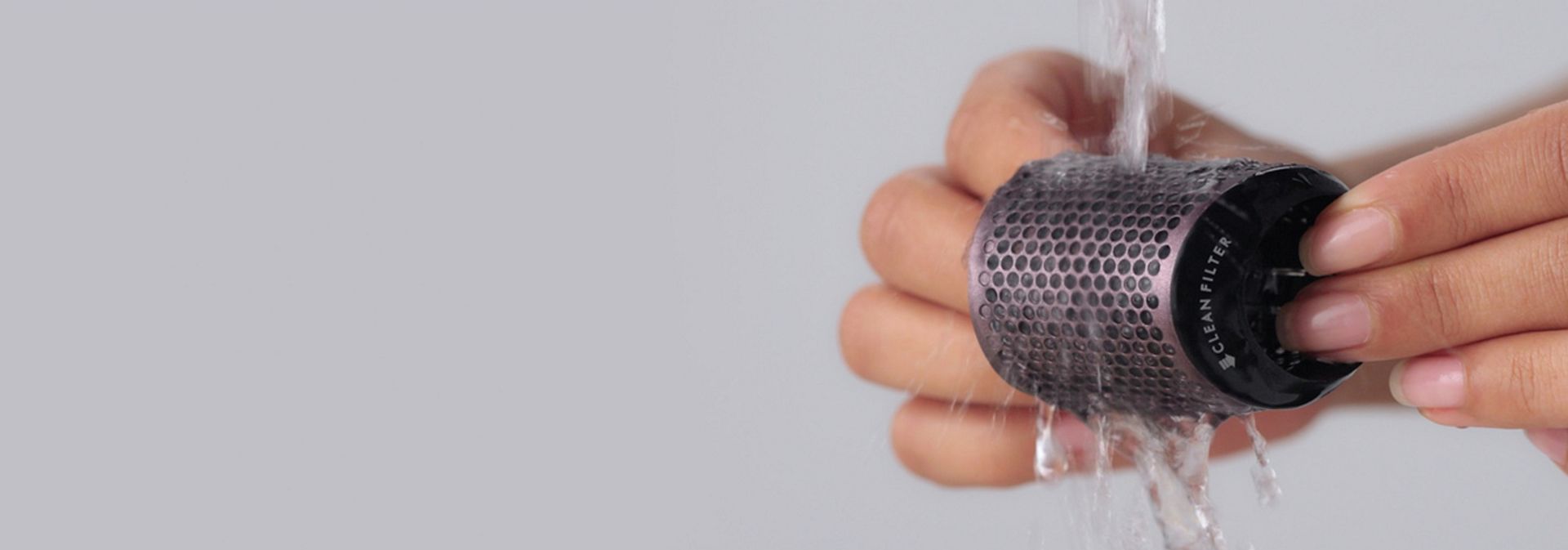 The filter of the Dyson Supersonic Travel hair dryer is rinsed under running water.