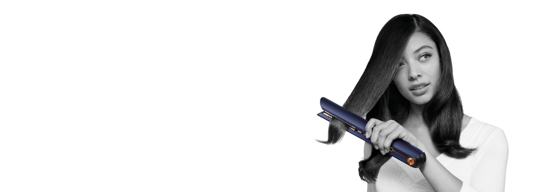 Model straightens her hair with the Dyson Corrale straightener.
