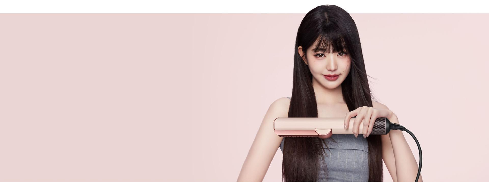 Model uses the Dyson Airstrait dryer and straightener to straighten and smooth her hair.