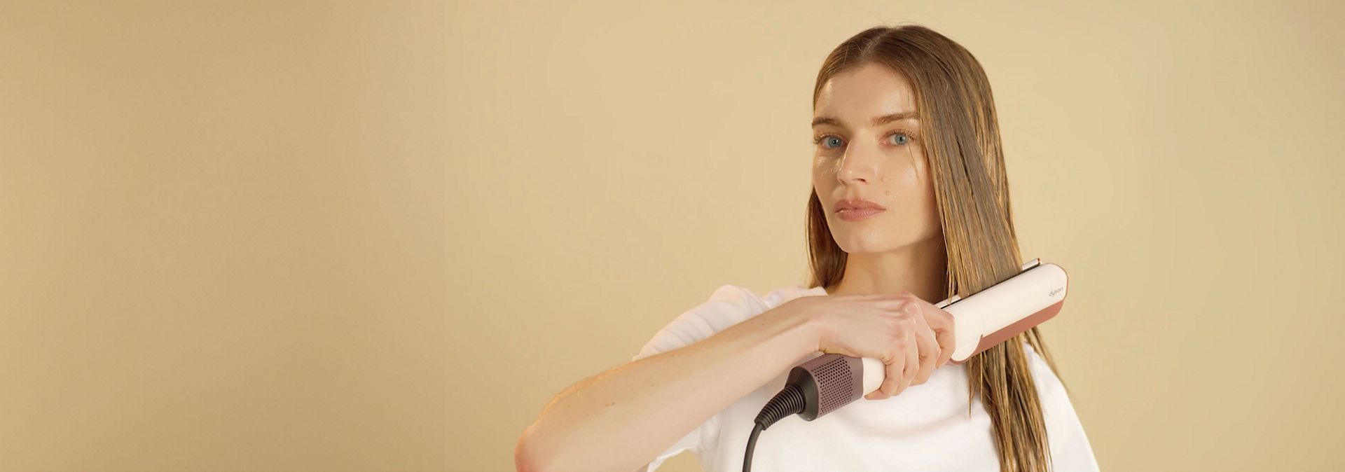 Model straightens her hair with the Dyson Airstrait dryer and straightener.