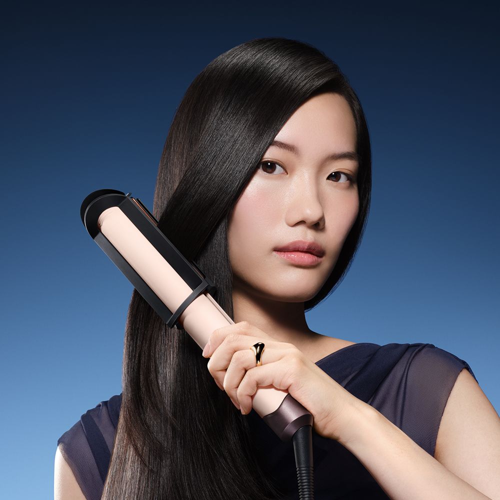 Model straightens her hair with the Dyson Corrale CoolShine hair straightener.