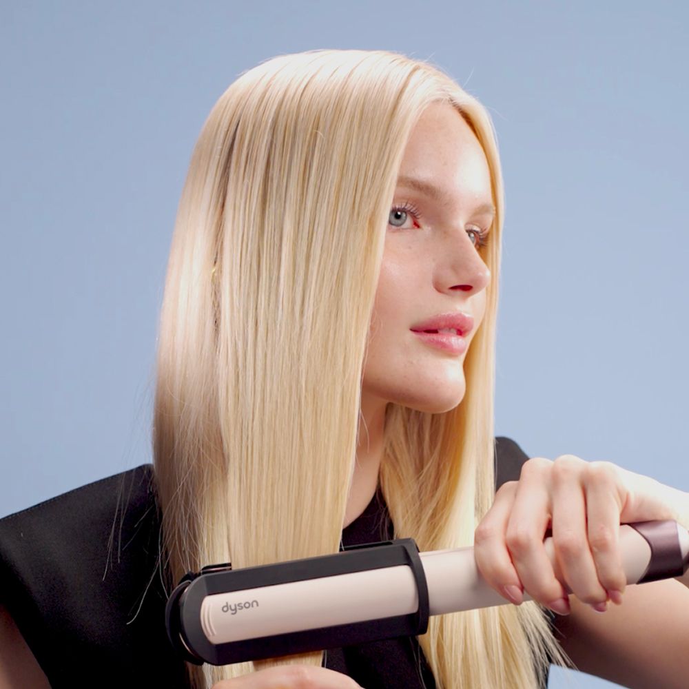 Model smooths her hair using the Dyson Corrale CoolShine hair straightener.