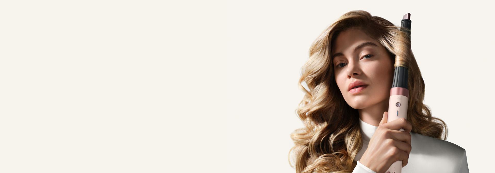 Model curls her hair with the Dyson Conical curling barrel.