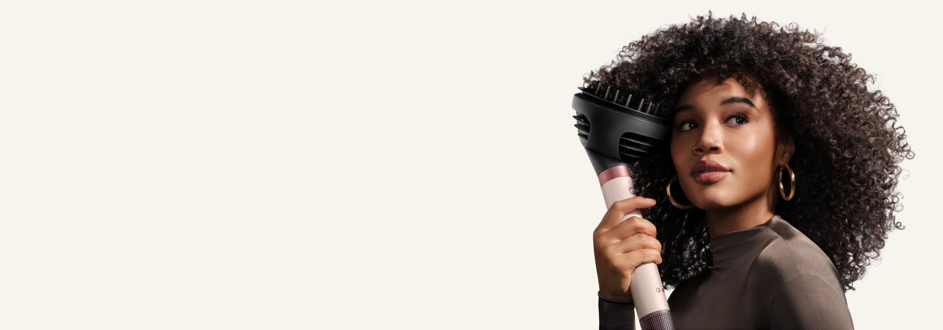 Model diffuses her hair with the Dyson Wave+Curl diffuser 2x.