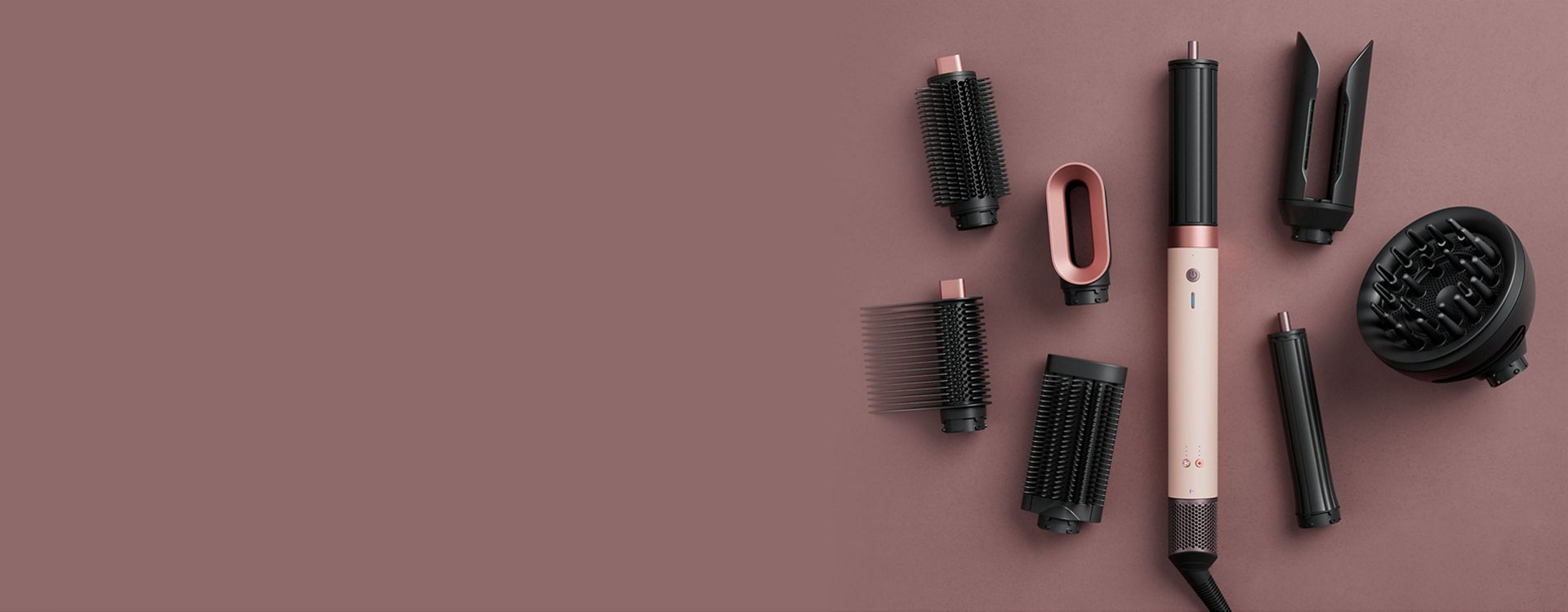 Dyson Airwrap Co-anda2x multi-styler and dryer surrounded by attachments.