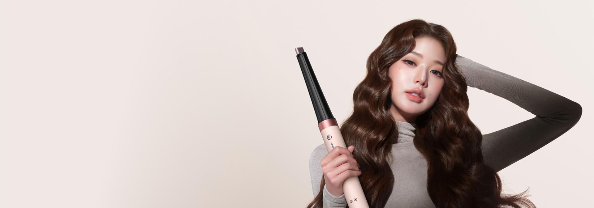 Model curls her hair with the Dyson Conical curling barrel.