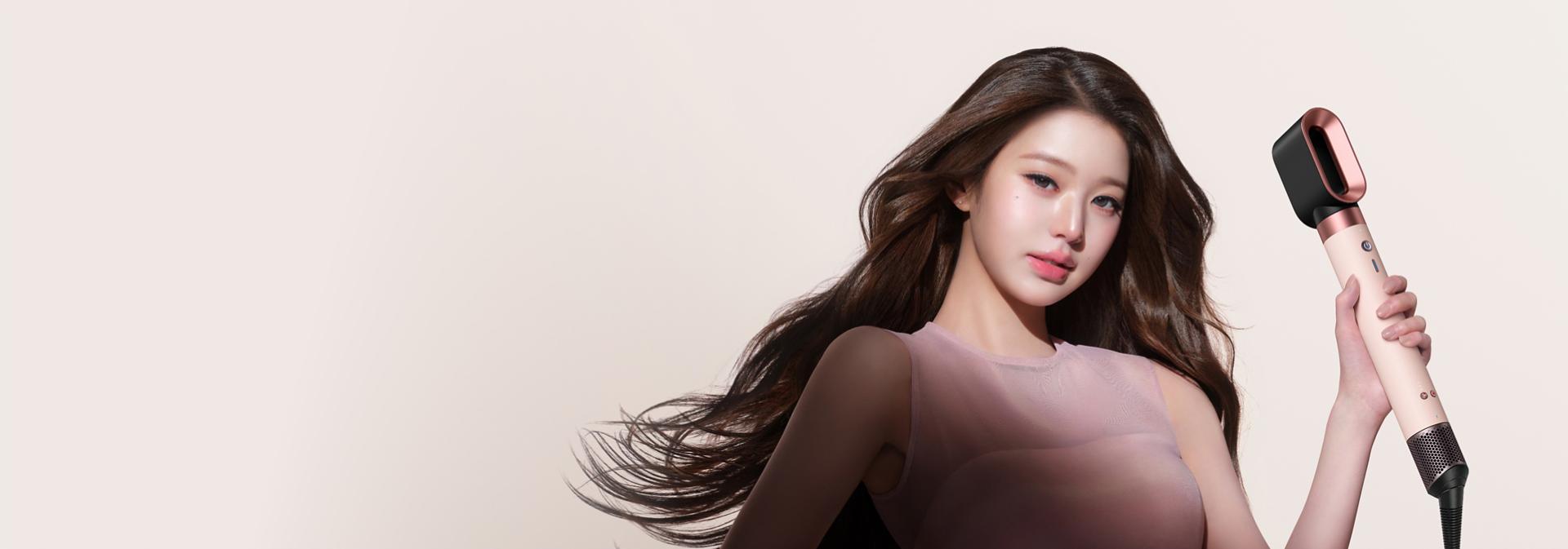 Model dries her hair with the Dyson Fast dryer 2x attachment.
