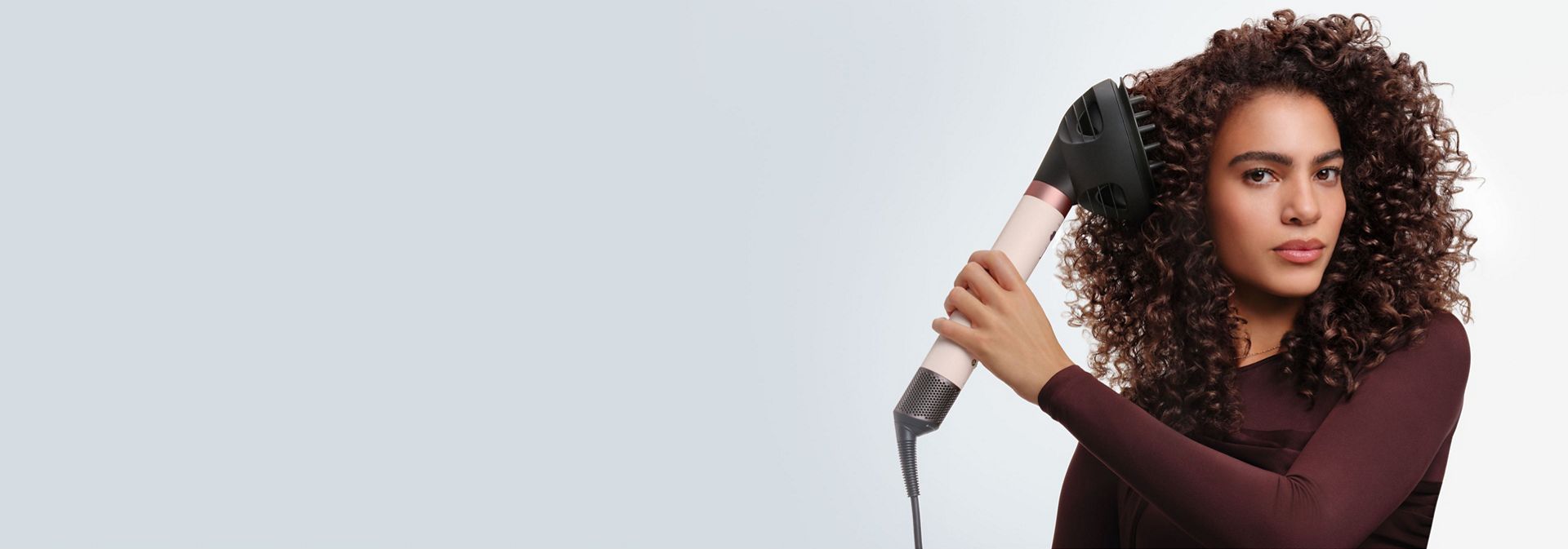 Saçını Dyson Airwrap Co-anda2x saç şekillendirme ve kurutma seti ile kurutan bir model.