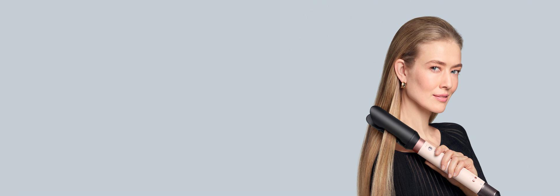 Modelka si vlasy vyhlazuje a narovnává pomocí nástavce Dyson AirSmooth2x™.