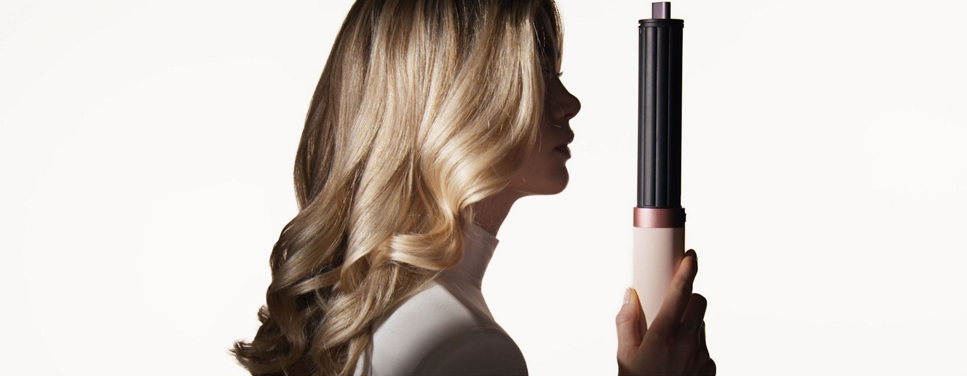 Model next to the Dyson Airwrap Co-anda2x multi-styler and dryer.