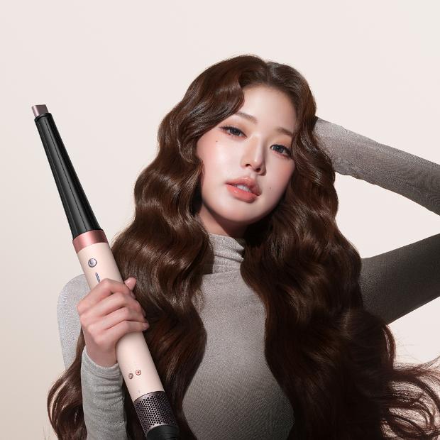 Jang Won-young holding the Dyson Airwrap Co-anda2x multi-styler and dryer with the curling barrel.