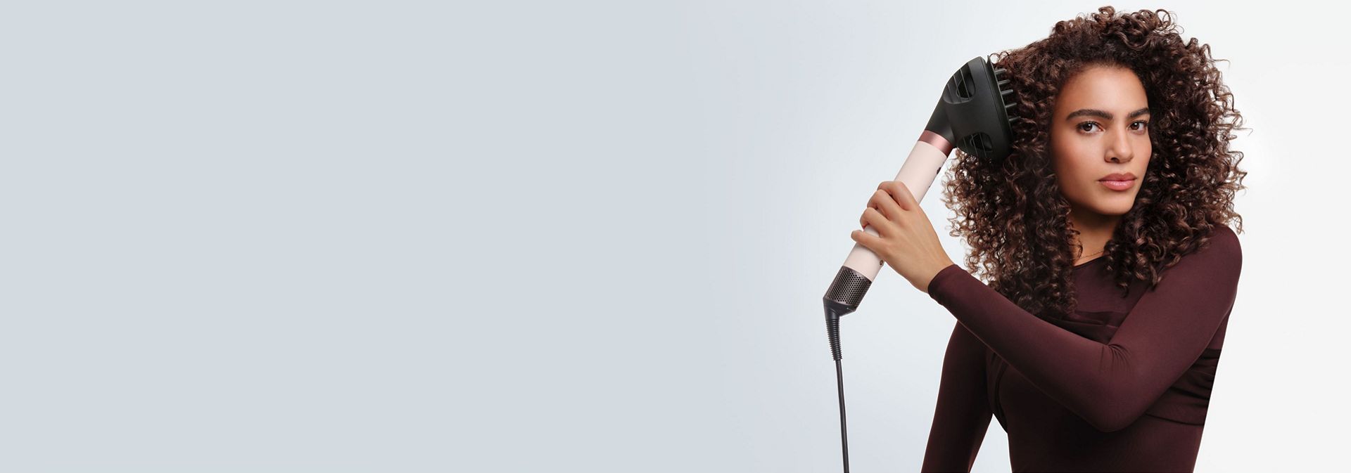 Model styles her hair with the Dyson Airwrap Co-anda2x multi-styler and dryer.