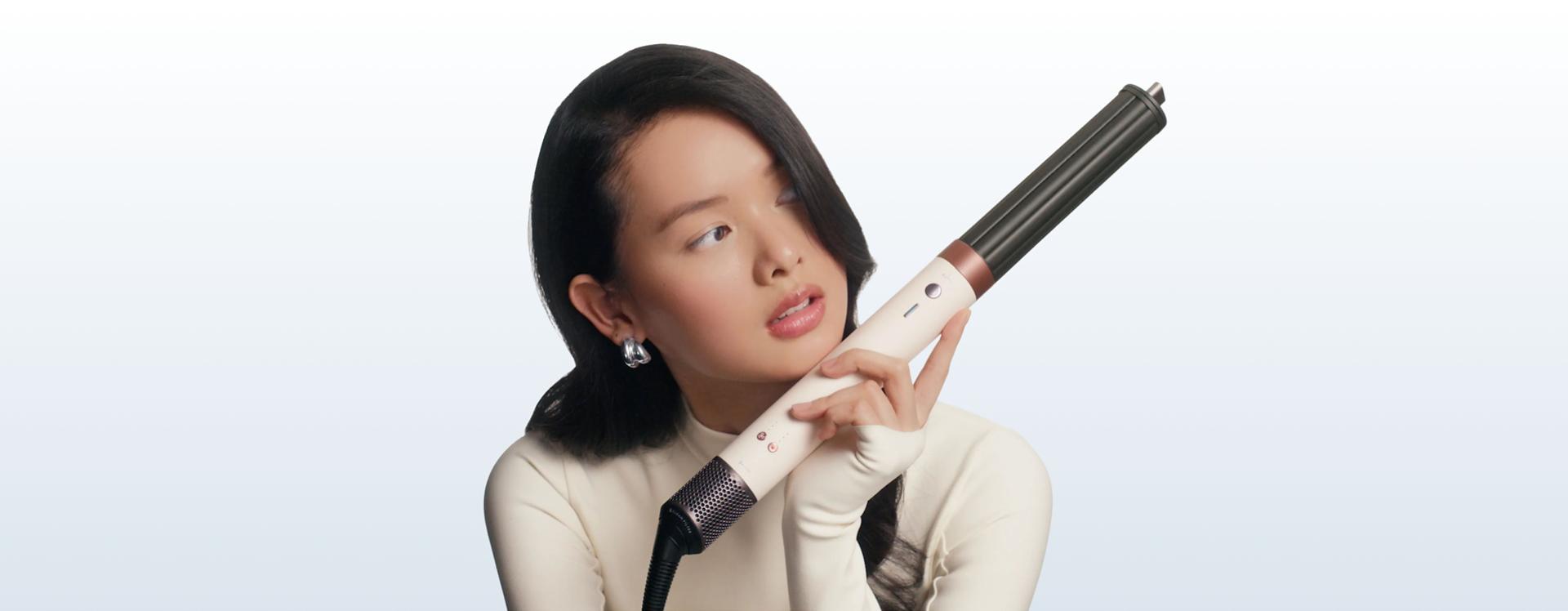 Model holds the Dyson Airwrap Co-anda2x multi-styler and dryer to one side.