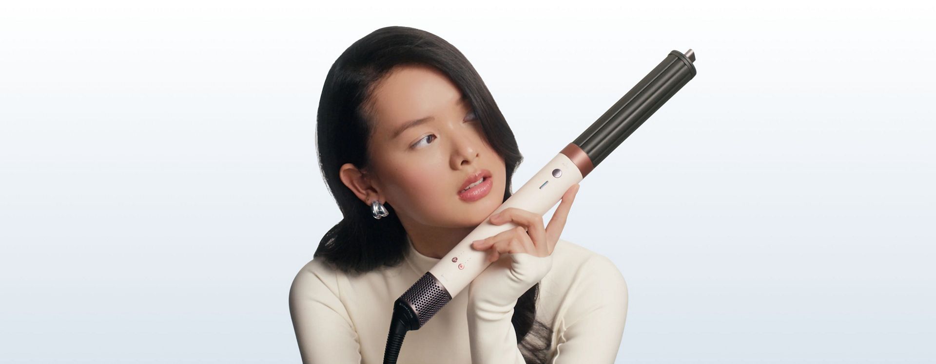 Model holds the Dyson Airwrap Co-anda2x multi-styler and dryer to one side.
