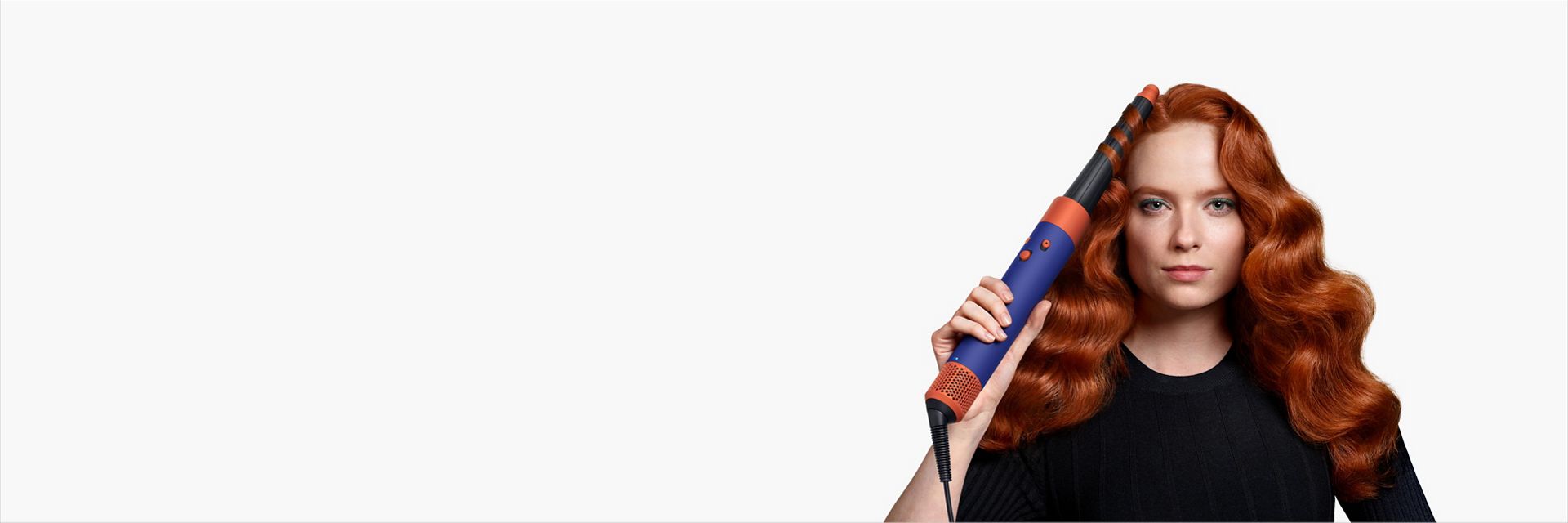 A model with long red hair uses the Conical Airwrap barrel to add waves to her hair.