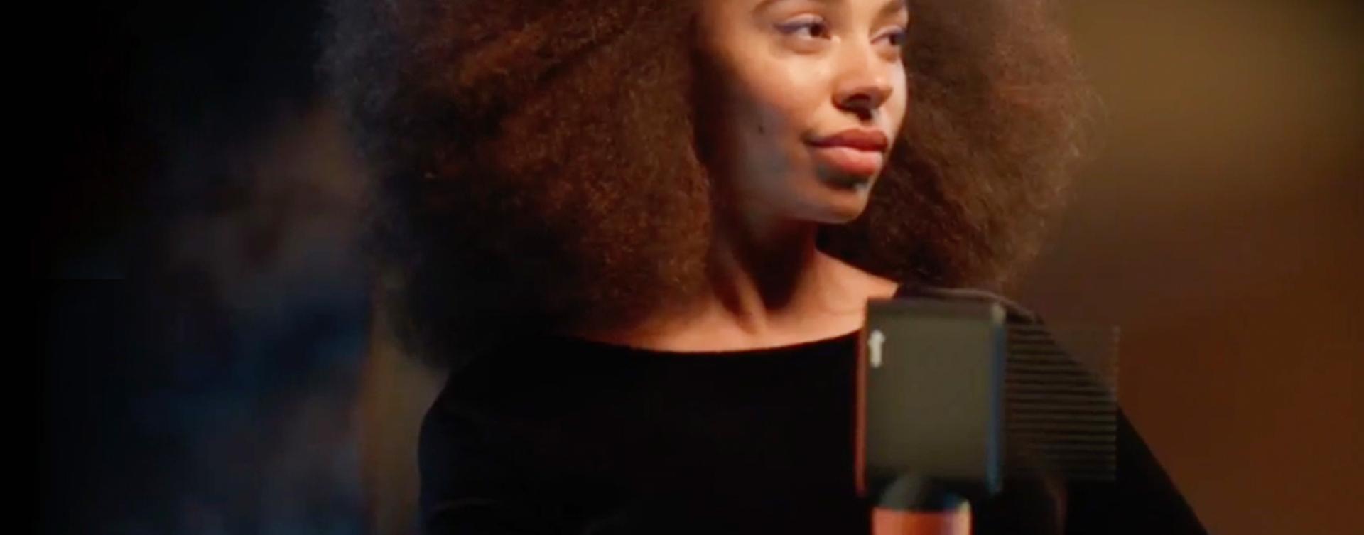 A model with brunette coily hair in a stretched blowout style holding the Dyson Airwrap i.d. multi-styler and dryer.