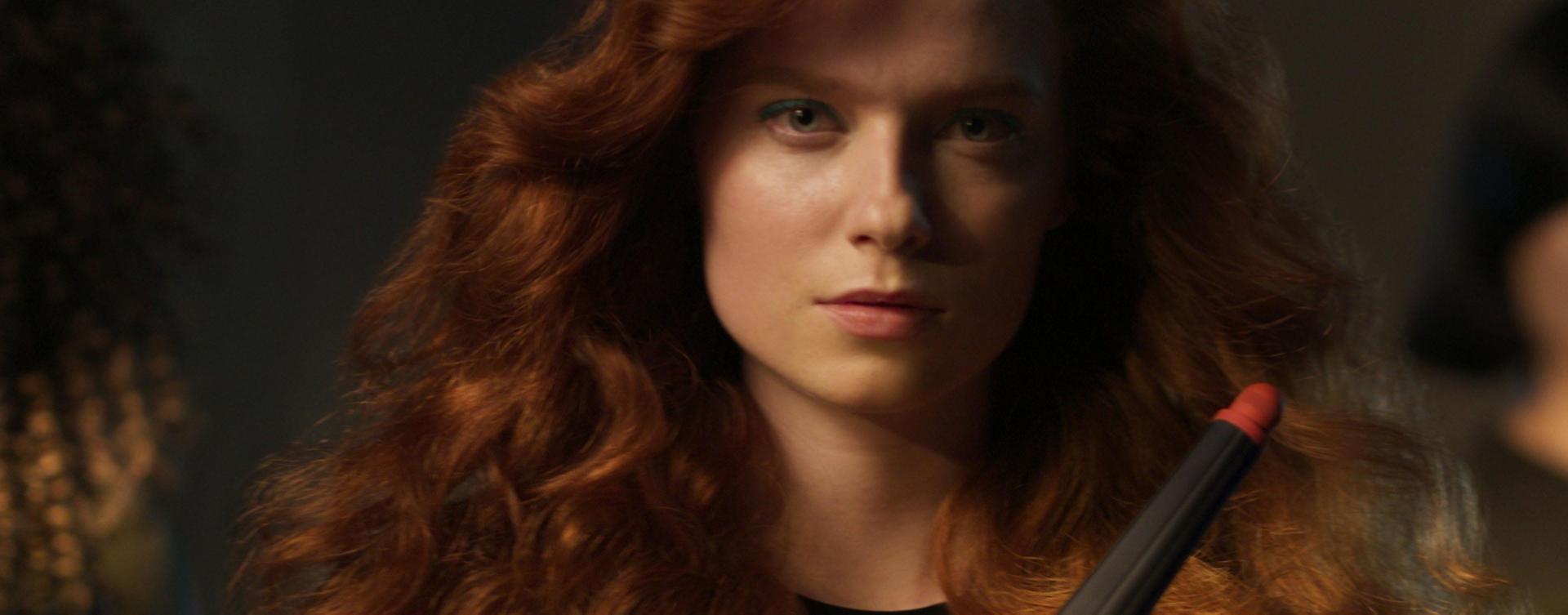 A redhead model shows off her wavy hair, styled using the Conical Airwrap barrel attachment.