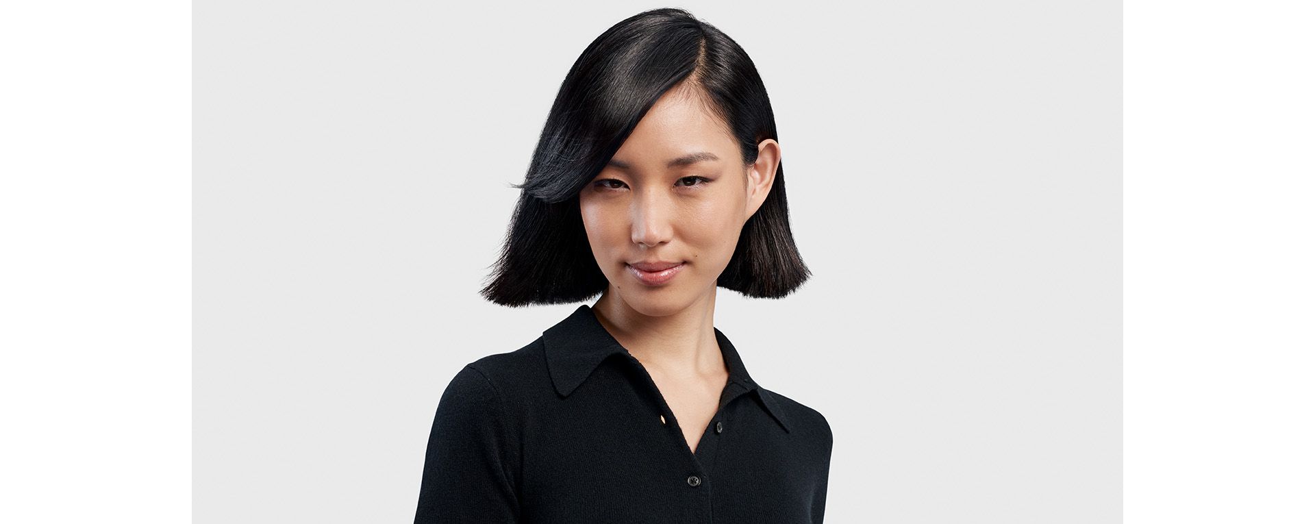 A model with medium length black hair styled into a short sleek bob.