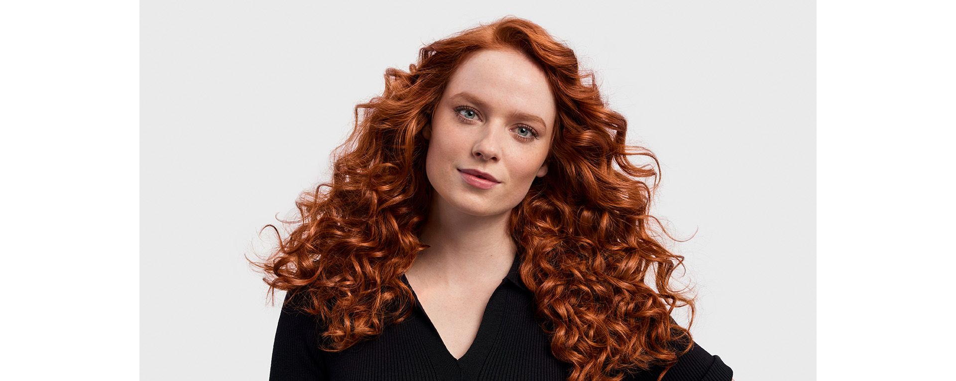 A redhead model with her long hair styled into '80s-style curls.