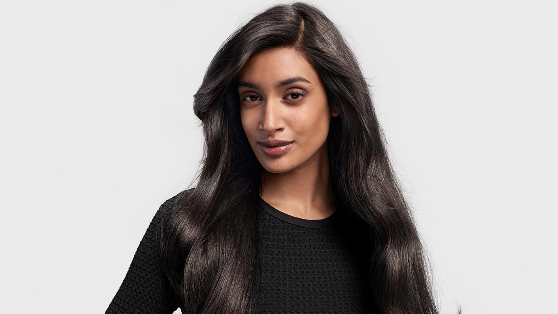 A dark-haired model with long hair styled in a ’90s blowout.