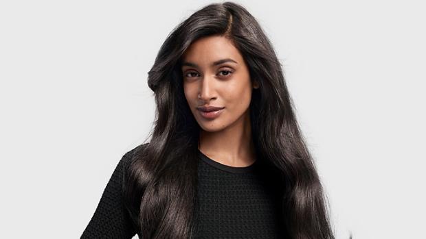 A dark-haired model with long hair styled in a ’90s blowout.