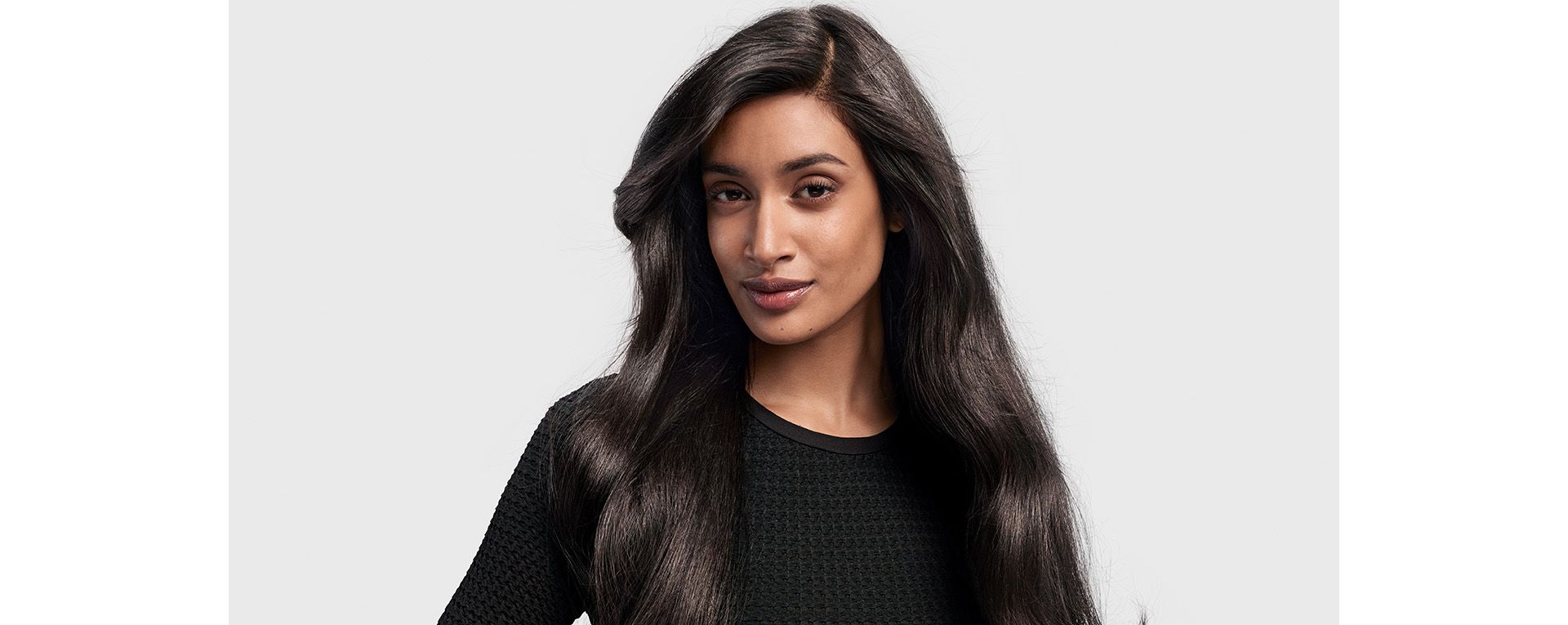 A dark-haired model with long hair styled in a ’90s blowout.