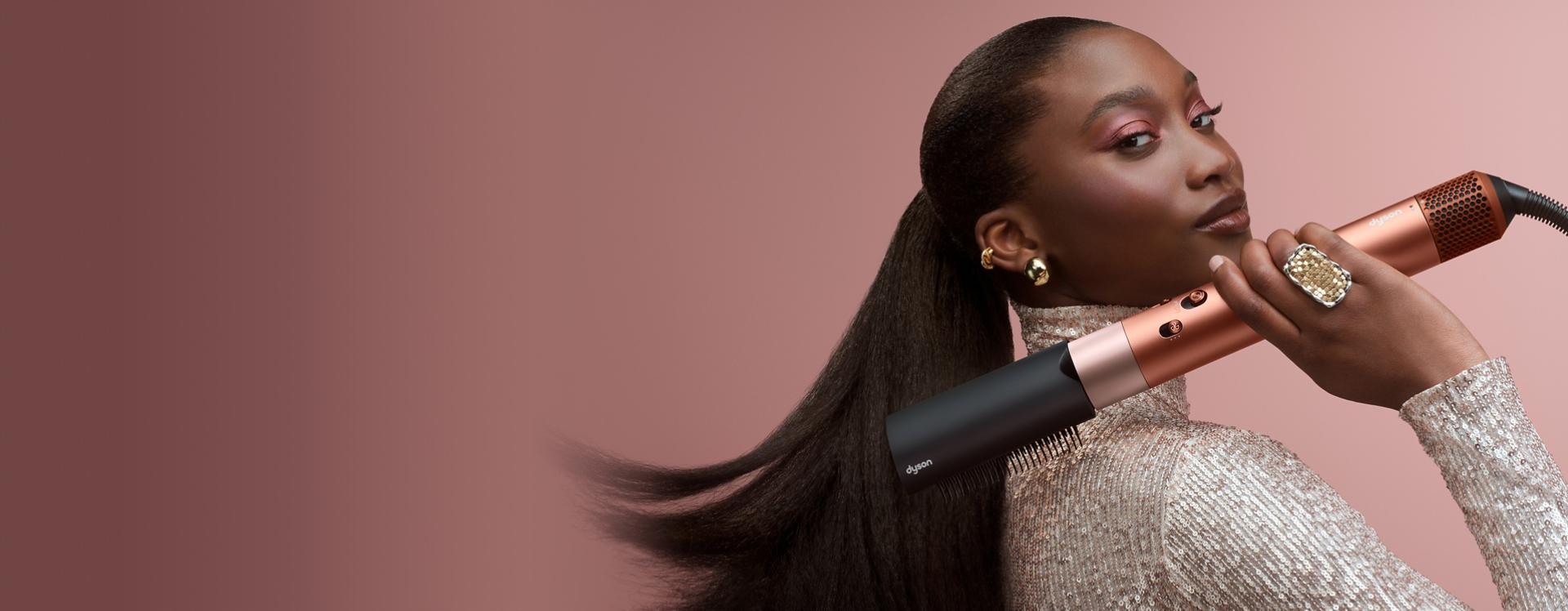 Egy modell a Dyson Airwrap ID multifunkciós hajformázó-szárítóval fésüli a haját.