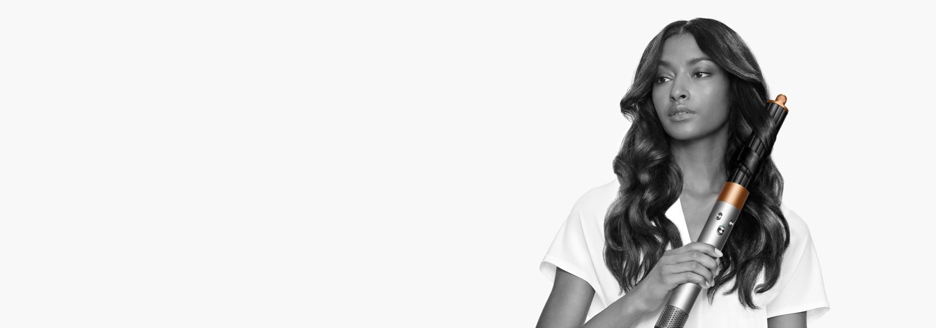 A brunette model smooths flyaways with her Dyson Airwrap Origin multi-styler and dryer.