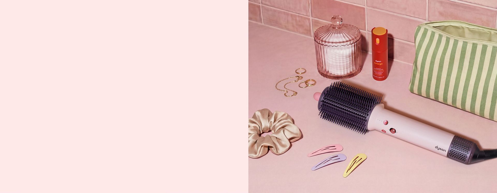 Dyson Airsmooth styling brush next to hair clips and a toiletries bag.