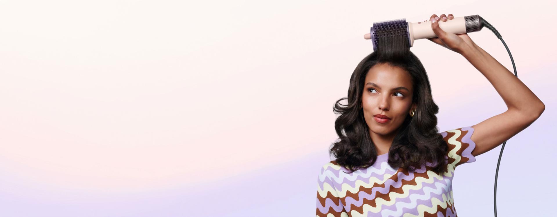 Model styles her hair with the Dyson Airsmooth styling brush.