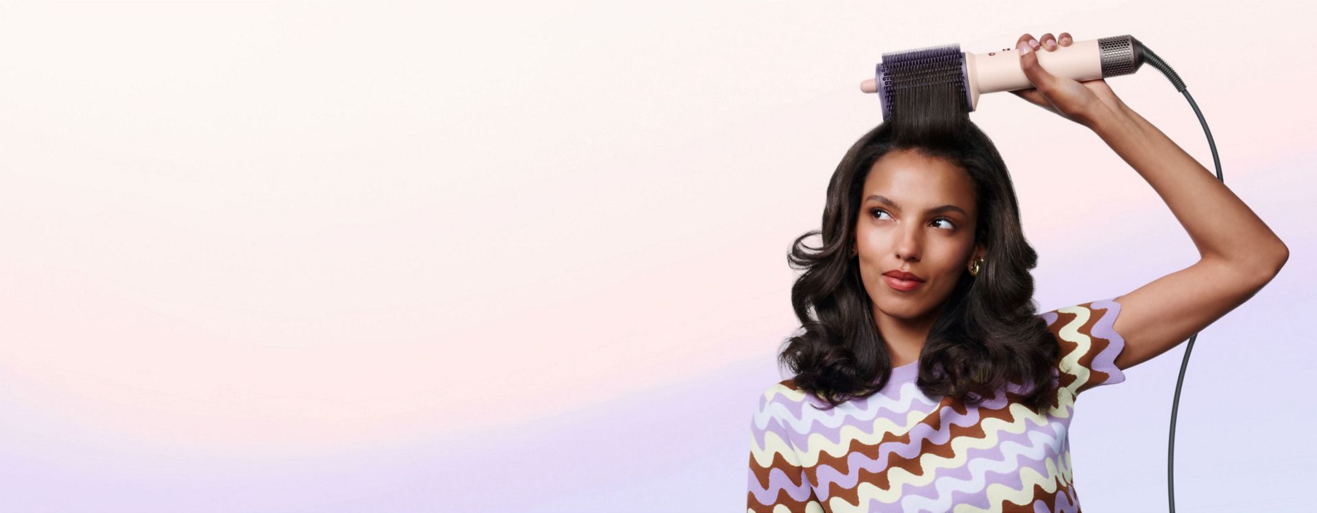 Model styles her hair with the Dyson Airsmooth styling brush.