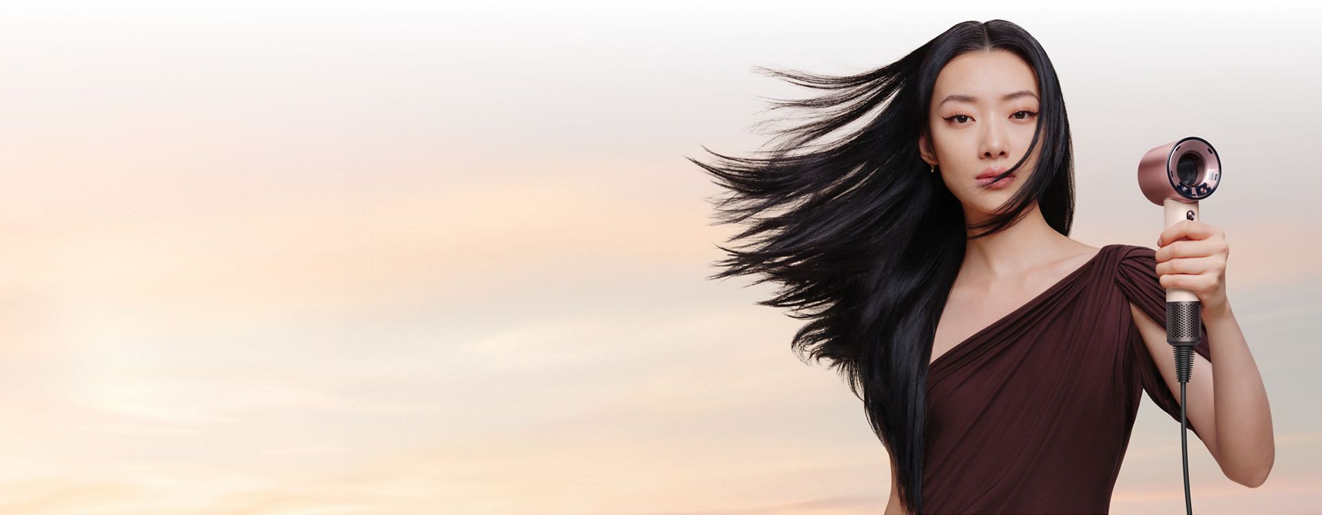 Model holds the Dyson Supersonic Travel hair dryer.