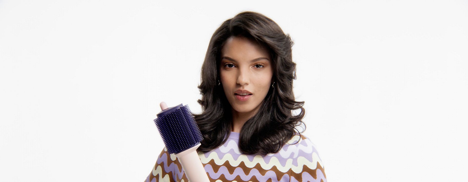 Model with styled hair holds the Dyson Airsmooth styling brush.