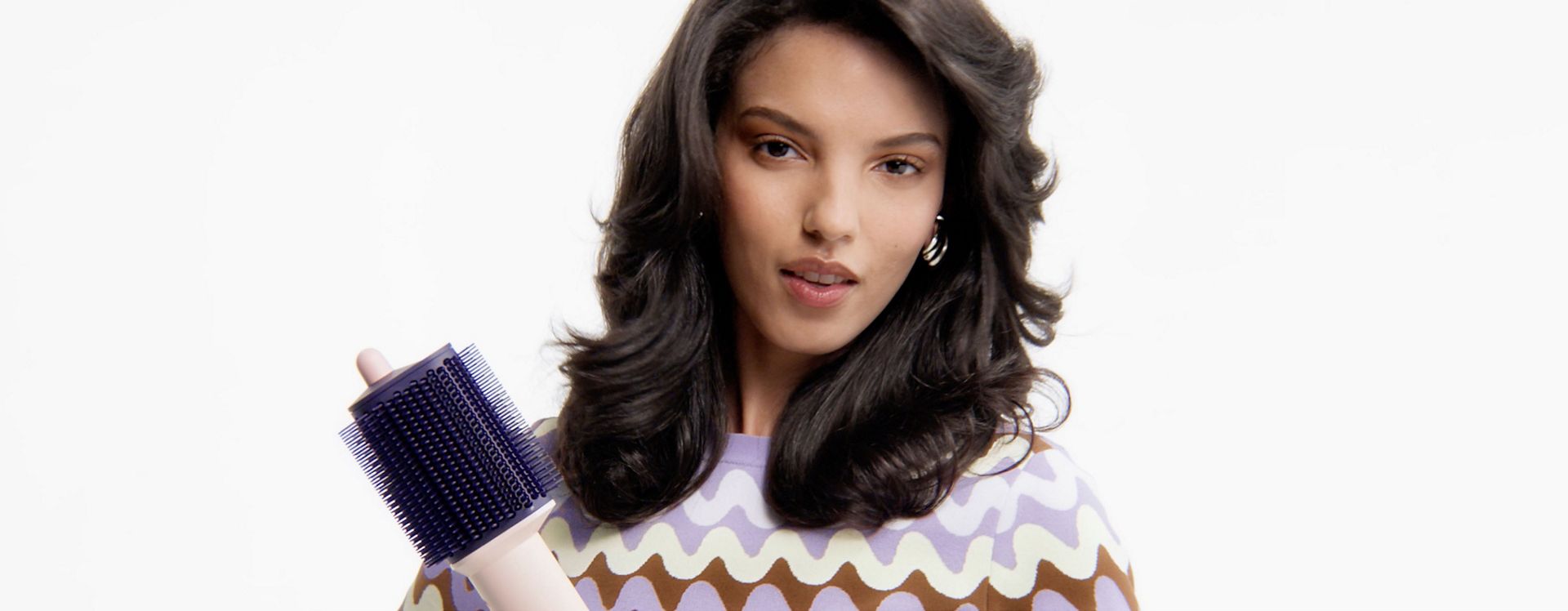 Model with styled hair holds the Dyson Airsmooth styling brush.
