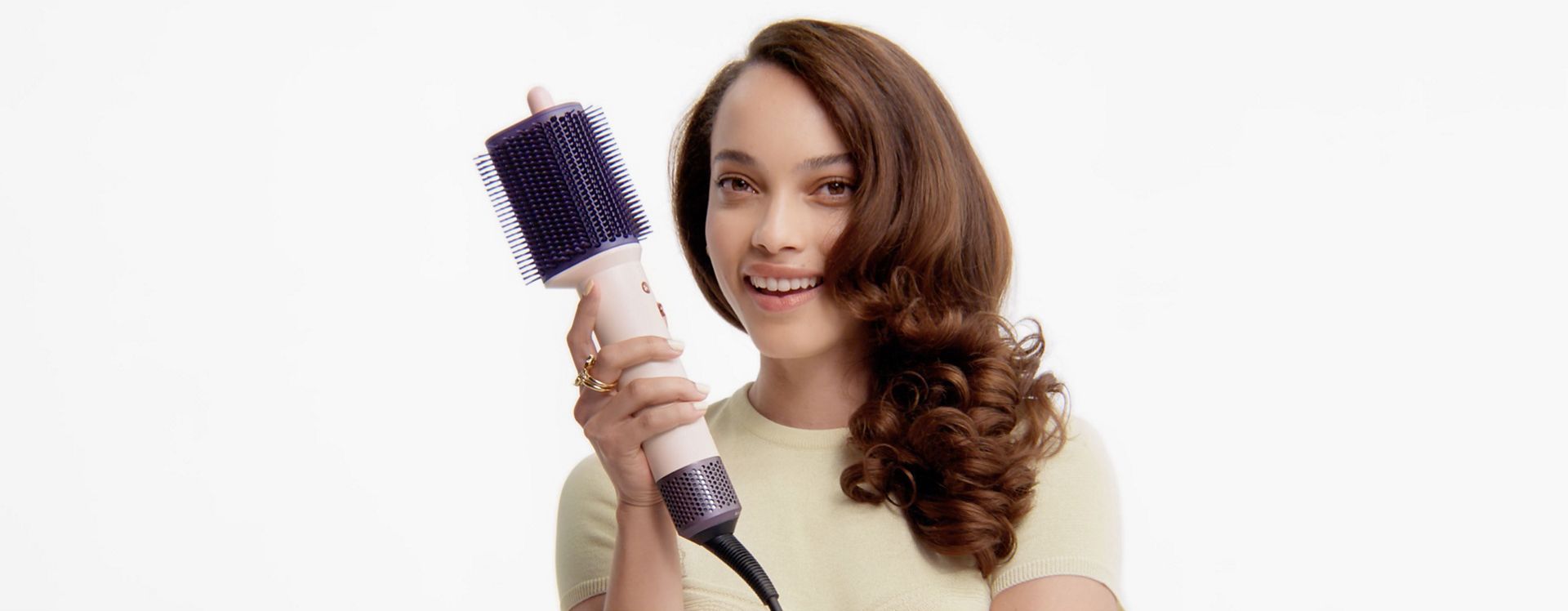 Modelis su suformuotais plaukais laiko „Dyson Airsmooth“ formavimo šepetį.