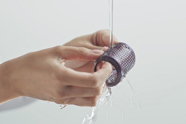 The filter of the Dyson Airsmooth styling brush is cleaned under running water.