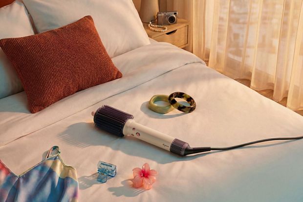 Dyson Airsmooth styling brush on a hotel bed.