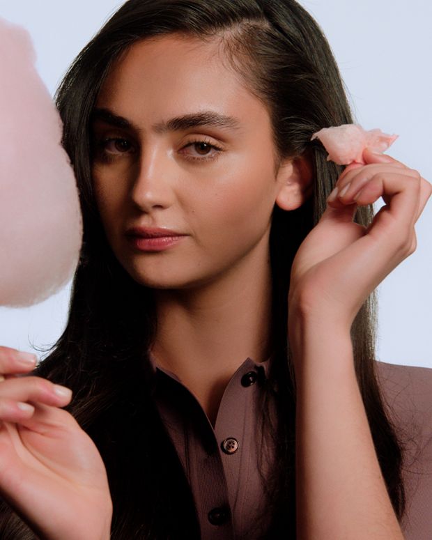 Model shows off styled hair while holding cotton candy.