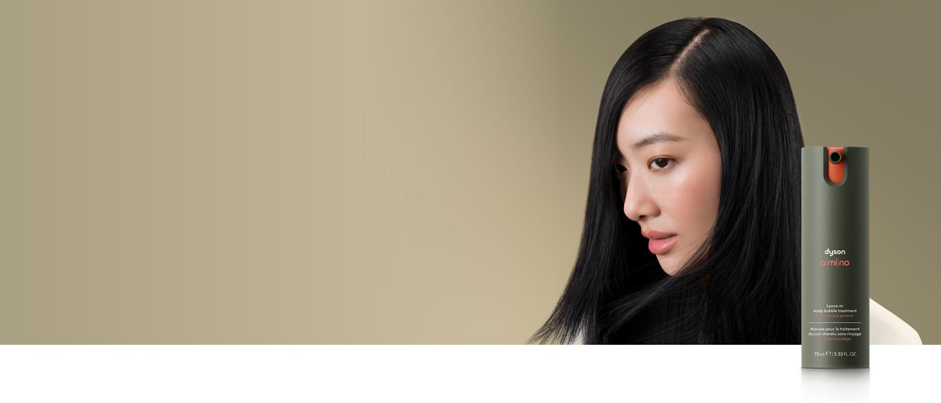 A straight haired model behind the Dyson Amino™ scalp care range.