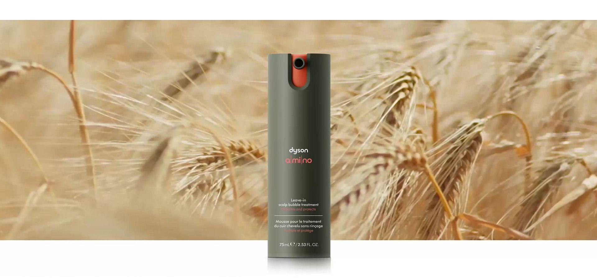 Dyson Amino leave-in scalp bubble treatment in front of barley growing in a field.