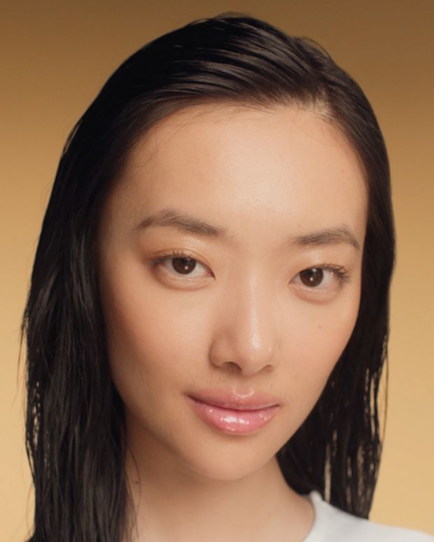 A model applying Dyson Amino leave-in scalp bubble treatment to her hair.