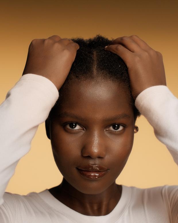 A model applying Dyson Amino leave-in scalp bubble treatment to her hair.