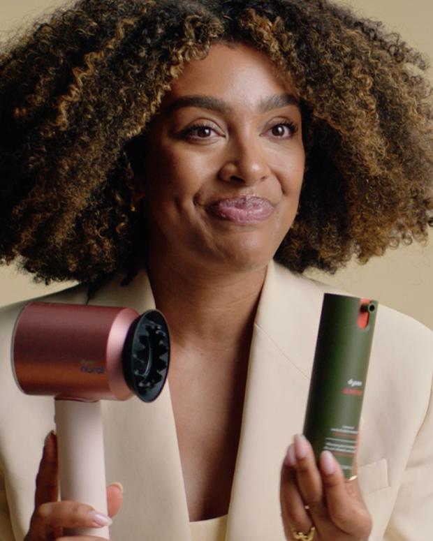A stylist holds the Dyson Supersonic Nural hair dryer and Dyson Amino leave-in scalp bubble treatment.